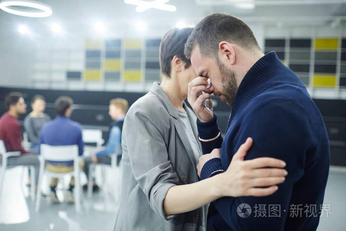友好的女人拥抱绝望的男人,带着队友的眼泪
