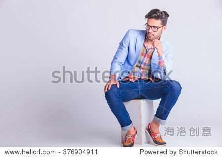smart casual man seated on box, wearing glasses