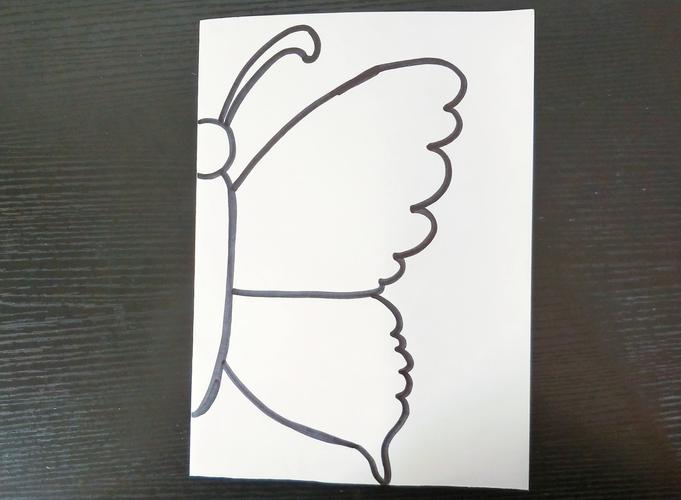 第一步:白纸对折,在连接面画半只蝴蝶.