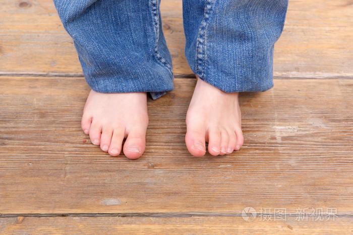 小女孩赤着脚在木地板上