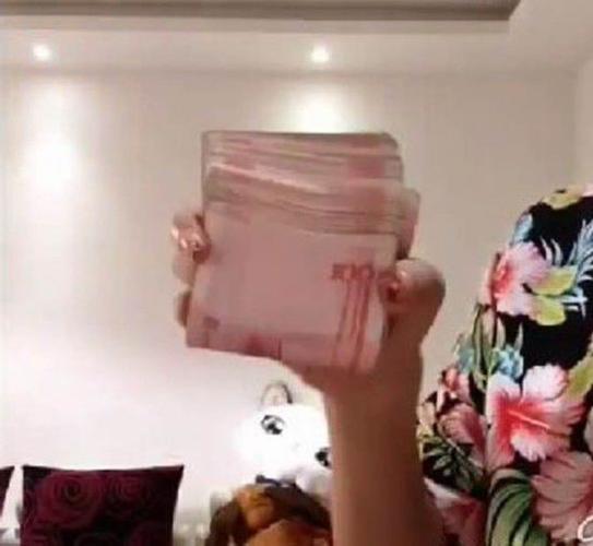 这位女士先将一沓钱对折单手握住.