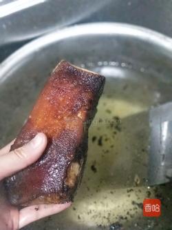 把烧过的腊肉在水里泡3到4个小时以上,然后用刀把烧焦泡涨的皮刮掉,用