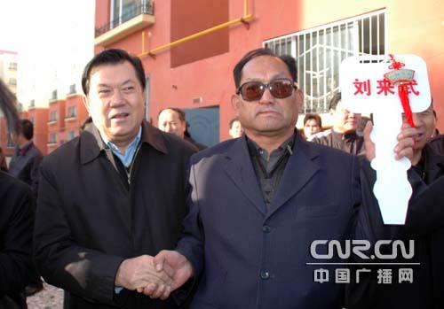 乌鲁木齐市市长乃依木·亚森为拆迁户发放新房钥匙