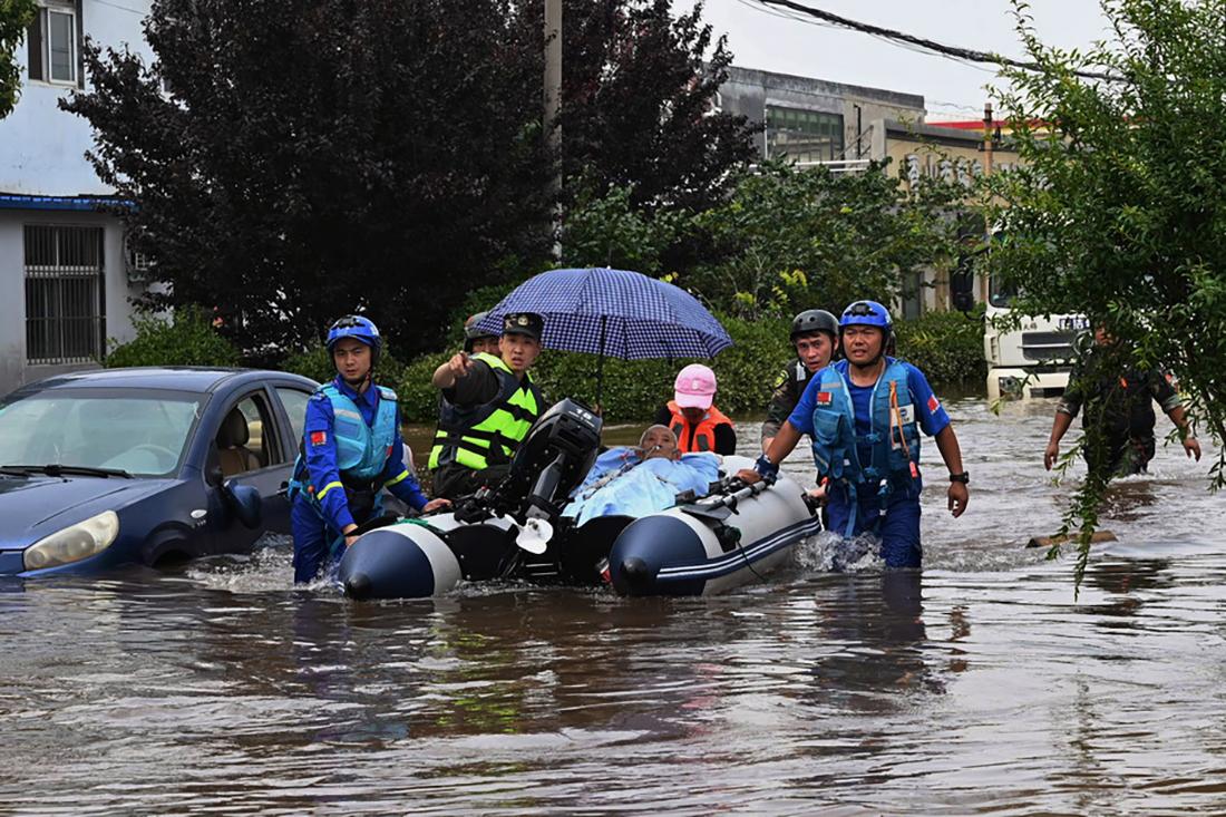 2021年7月25日,河南省新乡市和平大道,救援人员在积水中转移颐养院的