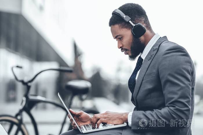 非洲商人戴着耳机工作