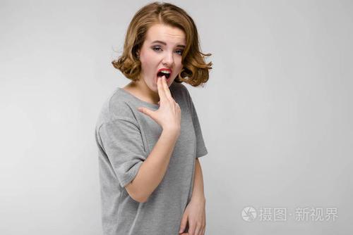 美丽的红发女孩的肖像愁眉苦脸的灰色背景