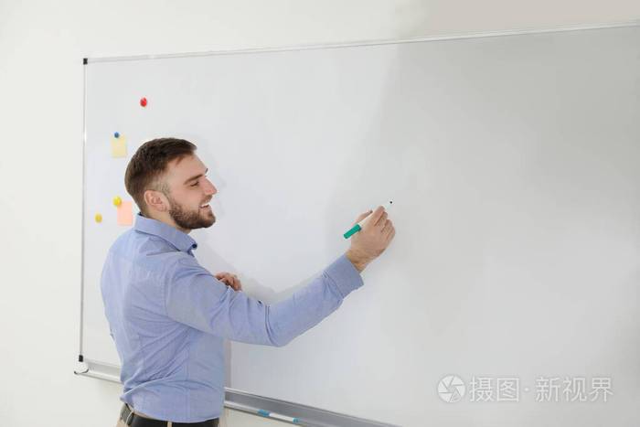 年轻教师在教室白板上写字的画像