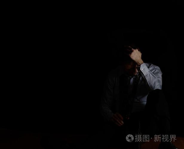 坐在成熟的男人拿着啤酒瓶在达累斯萨拉姆时按住头