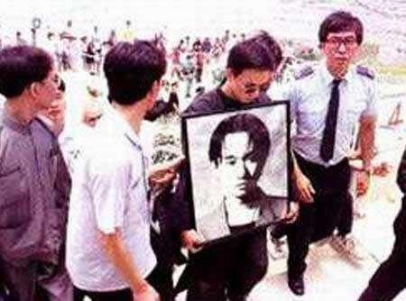 黄家驹的弟弟黄家强双手捧着遗像.下葬时,吉他陪着家驹一起长眠于此.