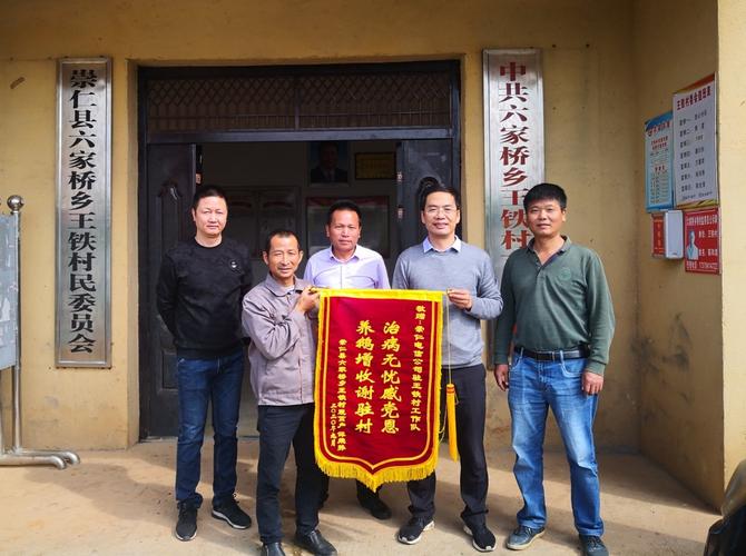 图为村民谭荣孙(左二)来到村委会给驻村第一书记李振华(右二)送锦旗