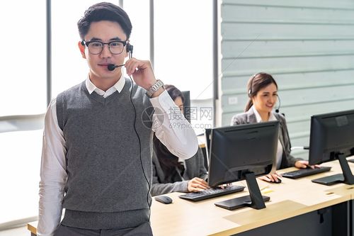 轻的成人,友好自信的接线员与耳机他的队呼叫中心工作,客户服务技术