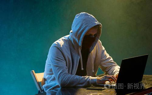 戴兜帽的电脑黑客窃取信息的笔记本电脑