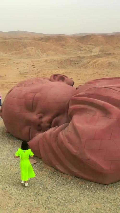 沙漠中巨婴雕塑就像沉睡在大地母亲的怀抱中旅行大玩家