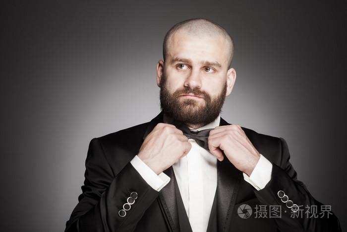 时尚和残酷秃头的男人,留着胡子的优雅的黑色西装