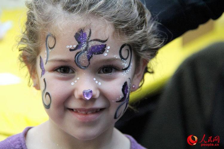 一名美国小女孩画完脸部彩绘后开心地笑了.本报记者 高石 摄