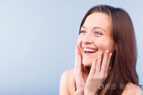 快乐的美丽女人侧着头. 孤立的蓝色背部