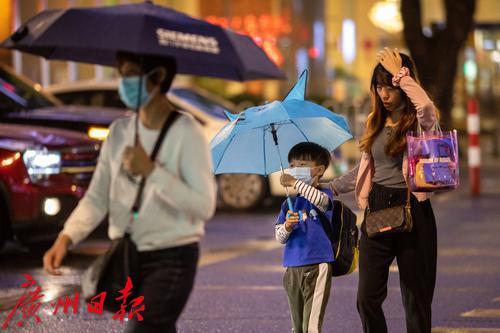 图为小雨中,小朋友撑着小伞过马路,妈妈则用手挡雨.
