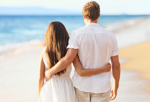 情侣相互抱着腰漫步在海边