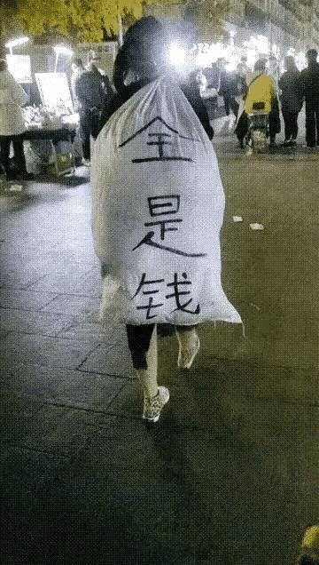 近日,广东广州,一女子扛着麻袋出现在大街上,麻袋上印着三个"全是钱"
