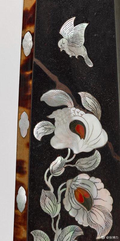 背面以螺钿装饰鸟蝶花卉纹,花蕊以金线描出,金线上再覆盖琥珀.