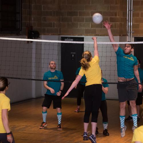 opposing teams both try and spike the ball over the volleyball