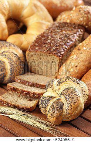 kaiser bread roll with poppy seeds on wooden table and ear of