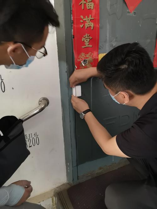 小组成员王腾配合社区工作人员为辖区居家隔离人员安装出入提示门磁.