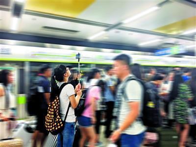 梅艳兰高举自拍杆,在北京西站地铁站搜集人群资料
