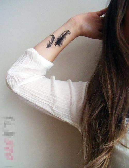 女生手腕上黑色点刺轻盈羽毛纹身图案