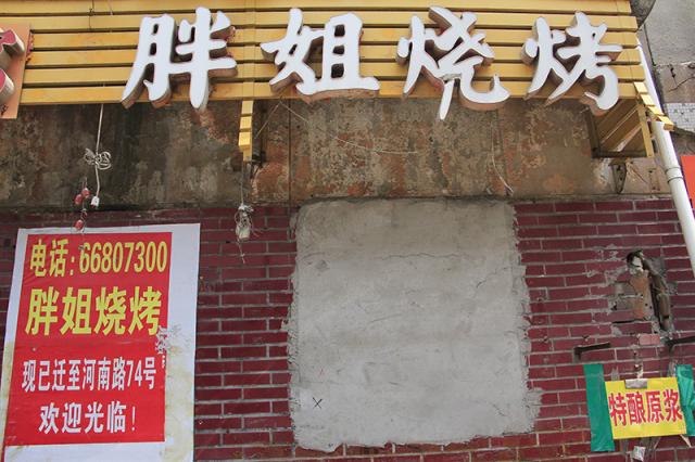 胖姐烧烤老店的门窗已经用水泥封砌,店外的墙上贴着迁址的告示.