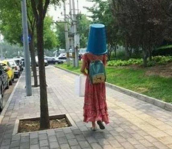 妹子,你怎么把垃圾桶套在头上,还能看得见走路么,可别摔跤了!