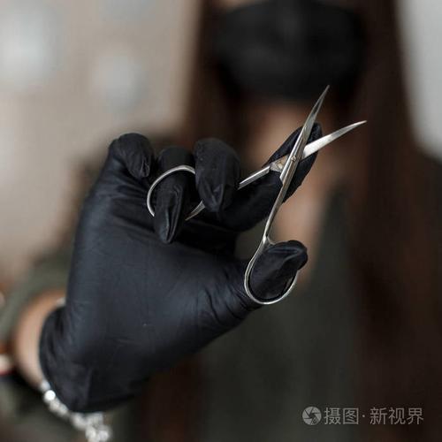 戴黑手套的女人拿着剪刀.指甲护理