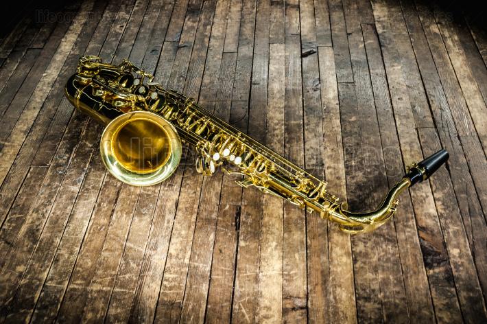 golden saxophone wind instrument on wooden brown stage