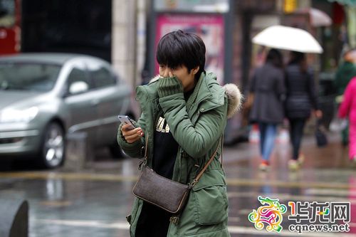 这妹子一边玩手机,一边哈气取暖. 首席记者 罗嘉 摄