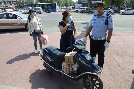 一位女士骑电动车载人,两位均未佩戴头盔,交警拦停警告.