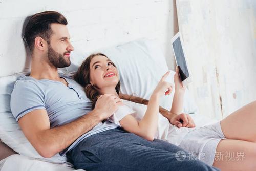 年轻的男朋友在床上拥抱女朋友,而女孩用手指指着数字