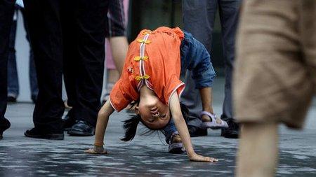 北京街头的一位小女孩正在表演杂技,以换得一些钱币
