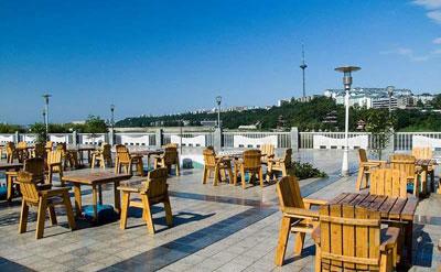 广场,公园一角或居民小区的空间地带,支上几把太阳伞,摆上桌椅和啤酒