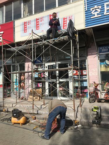路边商铺安装广告牌的工人