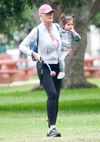 布里吉特·尼尔森戴粉色棒球帽搭配无痕裤,抱着娃健身