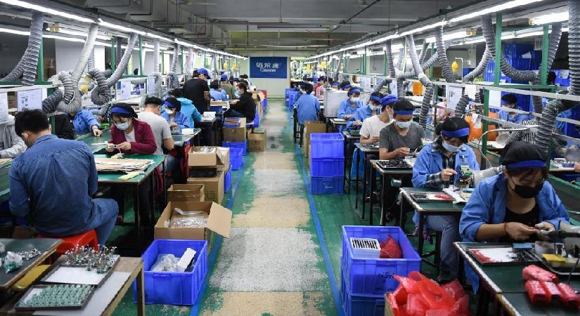 广州市倍尔康医疗器械有限公司车间内,工人在检查额温枪电路板