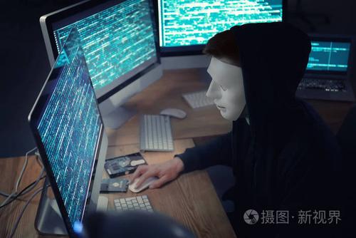 蒙面黑客使用电脑在黑暗的房间.网络攻击的威胁