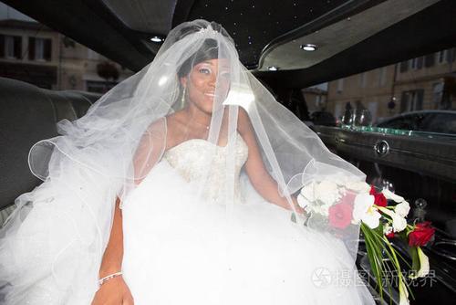 美丽的年轻的黑人美国新娘与白色面纱豪华豪华轿车