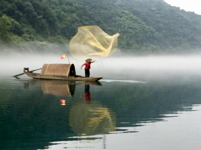 东江湖的薄雾很有观感,犹如轻沙盖水面,这水面偶见鱼夫在撒网捕鱼,雾