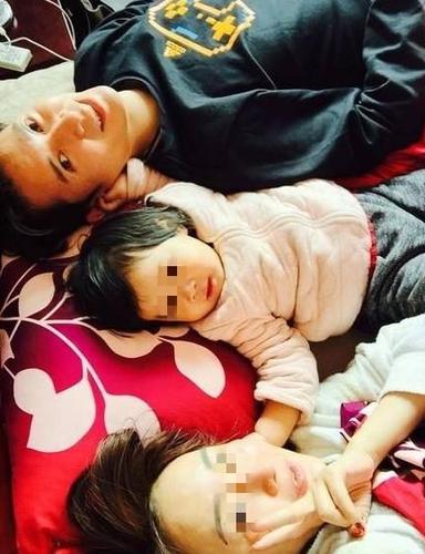 照片中韩栋和一个可爱的小女孩,以及一个年轻女子躺在床上,画面十分