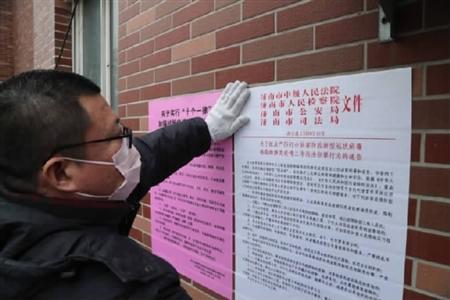 济南中院下沉社区进行防疫工作的干警在张贴公告.