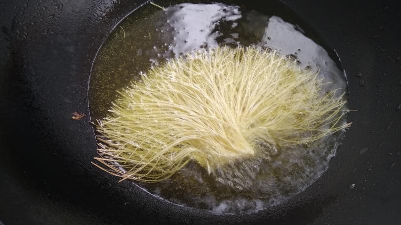 炒锅到适量油烧至8成热,用手拿住挂面粘过淀粉水的部分朝下炸制定型把