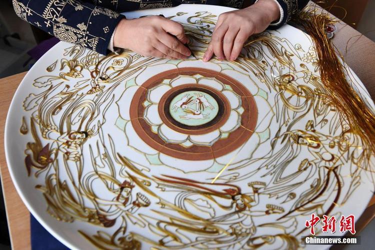 以敦煌壁画为范本制作掐丝珐琅壁画,并将作品搬入白色瓷盘里
