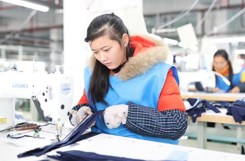 12月20日,在玉屏侗族自治县锦超服饰有限公司生产车间,工人在加工服装