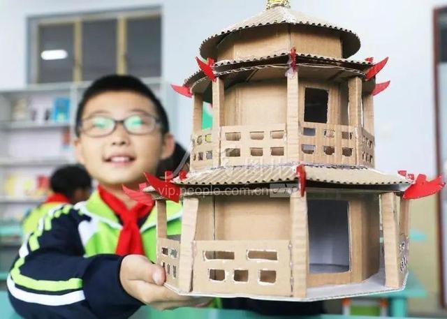 一名学生在展示用废旧纸箱制作的"宝塔".